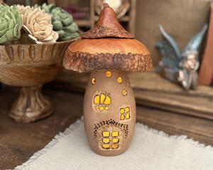 Mushroom fairy gourd house with carved windows that is lit up with a battery-operated candle. 